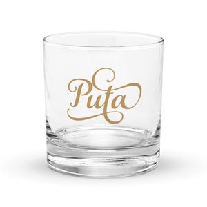 May include: A clear glass tumbler with the word "Puta" written in gold cursive lettering.
