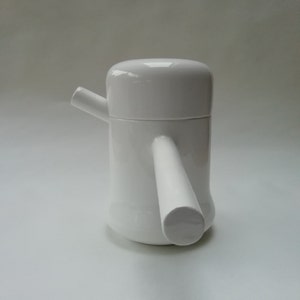 May include: White ceramic teapot with a unique handle and spout design. The teapot has a smooth, glossy finish.
