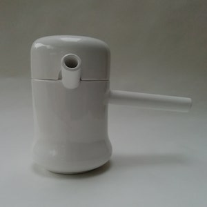 May include: White ceramic teapot with a spout and a handle. The teapot has a rounded body and a lid with a small opening for pouring.
