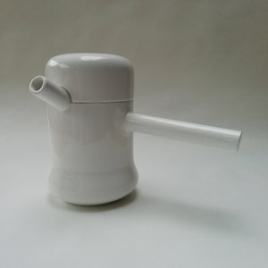 May include: White ceramic teapot with a spout and a handle. The teapot has a rounded body and a lid.