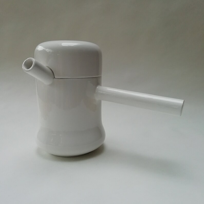 May include: White ceramic teapot with a spout and a handle. The teapot has a rounded body and a lid.