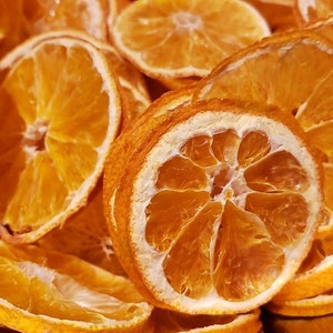 May include: A close-up of a bowl filled with dried orange slices. The orange slices are a vibrant orange color and have a translucent quality. They are arranged in a random pattern, creating a visually appealing display.