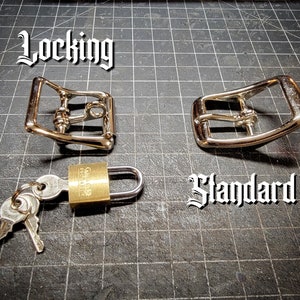 K&ouml;nnte beinhalten: Zwei silberne G&uuml;rtelschnallen aus Metall, eine mit der Aufschrift "Locking" und die andere mit der Aufschrift "Standard". Ein Messingvorh&auml;ngeschloss mit zwei Schl&uuml;sseln ist ebenfalls abgebildet.