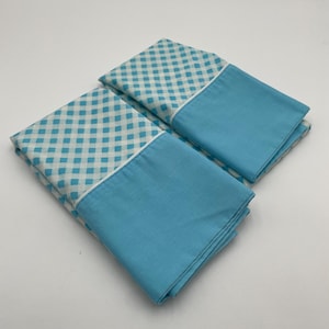 May include: Two blue and white gingham pillowcases with a solid blue border. The pillowcases are folded and stacked on top of each other.