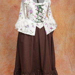 May include: A white and brown dress with a floral print and a lace trim. The dress has a fitted bodice with a lace-up front and a full skirt.