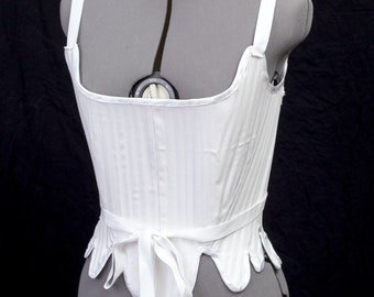 May include: White cotton corset with a fitted bodice and a gathered skirt. The corset has a ribbon tie at the waist and adjustable straps.
