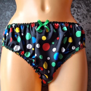 Puede incluir: Braga negra de satén con un colorido estampado de lunares en rojo, verde, amarillo y blanco. La ropa interior tiene un lazo y un ribete verdes.