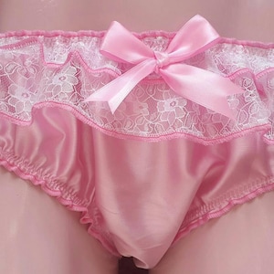 Peut inclure: Culotte en satin rose clair avec dentelle blanche et un nœud en satin assorti. Les bords sont froncés et le tissu doux crée un look délicat. Le design est féminin et confortable.