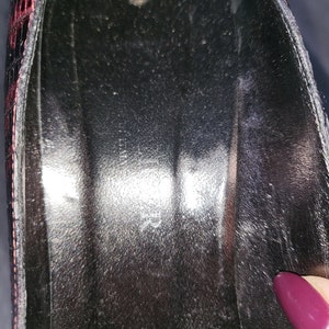 May include: Close-up of the inside of a black shoe with a red and black patterned design. The shoe is lined with a black fabric.