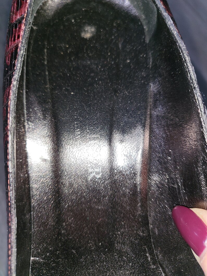 May include: Close-up of the inside of a black shoe with a red and black patterned design. The shoe is lined with a black fabric.