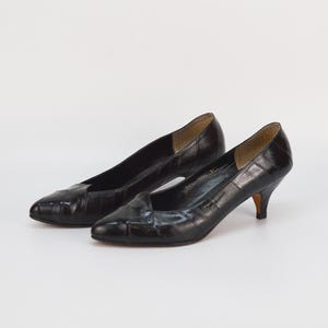 May include: A pair of black leather pumps with a pointed toe and a low heel.