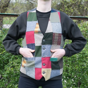 Può includere: Un gilet patchwork multicolore con una varietà di tessuti e trame. Il gilet ha una chiusura con bottoni e due tasche.