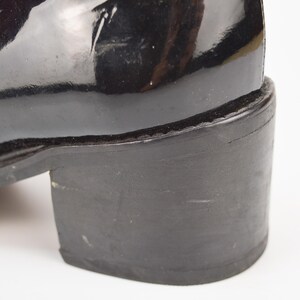 Puede incluir: Bota de tac&oacute;n de charol negro con una suela gruesa de goma negra.