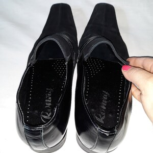 Puede incluir: Un par de zapatos negros de cuero con un empeine de ante negro. Los zapatos tienen una suela de cuero negro y una plantilla de cuero negro. La plantilla est&aacute; etiquetada como "Runway".