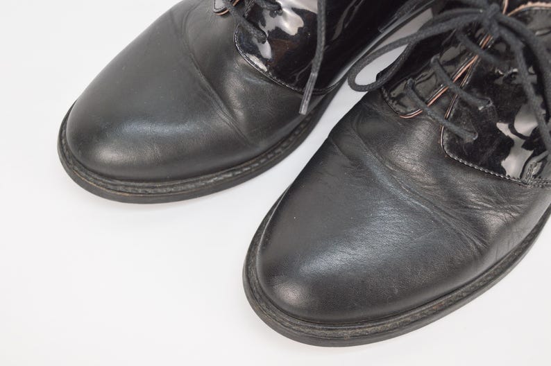 Puede incluir: Un par de zapatos negros de cuero con cordones y puntera de charol.