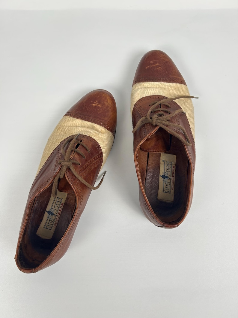 May include: A pair of brown and tan oxford shoes with a woven fabric panel. The shoes have brown laces and the brand name "King Street" is visible inside the shoe.