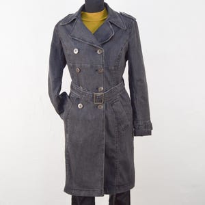 May include: A dark grey denim trench coat with a double breasted closure, a belt, and silver buttons.