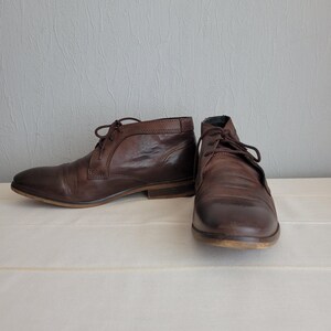 May include: A pair of brown leather ankle boots with laces. The boots have a rounded toe and a low heel.