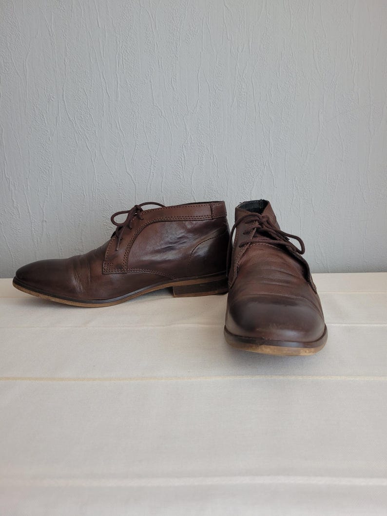 May include: A pair of brown leather ankle boots with laces. The boots have a rounded toe and a low heel.