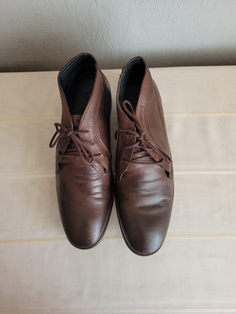 May include: A pair of brown leather ankle boots with lace-up closures.