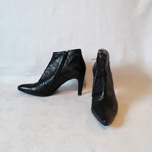 May include: A pair of black leather ankle boots with pointed toes and stiletto heels. The boots have a zipper on the inside of each boot.