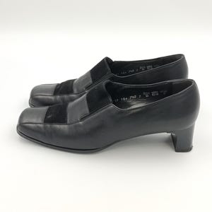 Puede incluir: Zapatos negros de cuero con un detalle de ante en la puntera y un tacón de bloque. Los zapatos tienen la talla 17, 18, 7HG, 7 y 38 escritos en la plantilla.