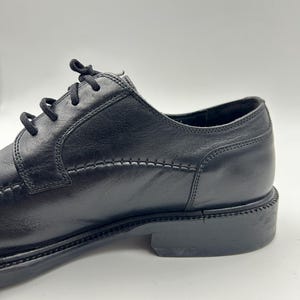 K&ouml;nnte beinhalten: Schwarzer Lederschuh mit Schn&uuml;rverschluss. Der Schuh hat ein gen&auml;htes Design entlang der N&auml;hte und einen niedrigen Absatz. Geeignet f&uuml;r formelle Anl&auml;sse.
