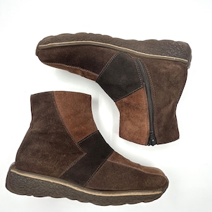 以下が含まれることがあります： 茶色のスエードアンクルブーツ2足。ブーツは、さまざまな茶色の濃淡とサイドジッパーを備えたパッチワークデザインです。ソールは、テクスチャード加工されたパターンを持つ濃い茶色です。