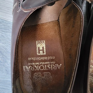 May include: Close-up of the inside of a brown leather shoe with the text "ARISTOKRAT den Svenska hertskon med laderinnersula" printed on the insole.