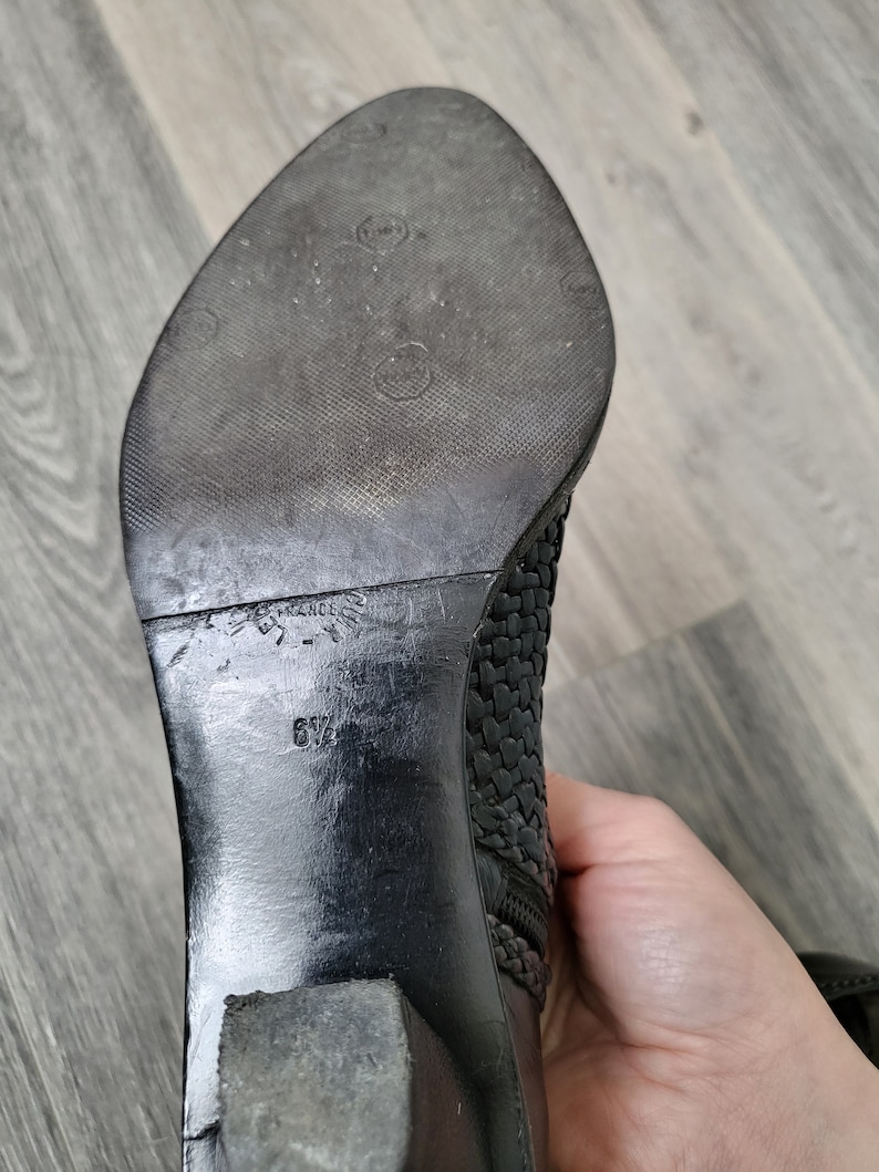 May include: Black leather ankle boots with a woven design and a zip on the side. The boots have a block heel and a size 6 1/2 printed on the sole.