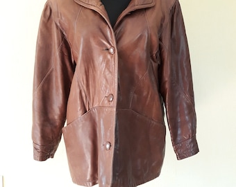 May include: A brown leather jacket with a button-up front and a collar. The jacket has a slightly oversized fit and features a quilted lining.