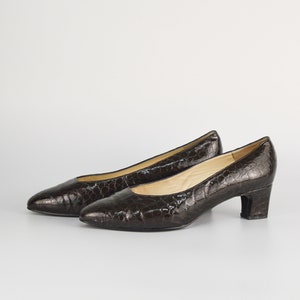 May include: A pair of brown leather pumps with a crocodile embossed pattern and a low block heel.