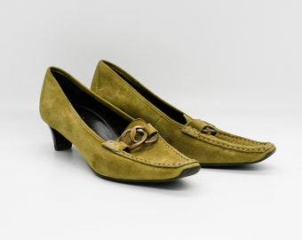 May include: A pair of green suede heeled shoes with a gold buckle detail. The shoes have a pointed toe and a low heel.