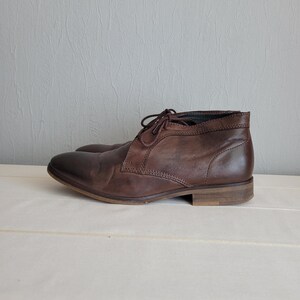 May include: Brown leather ankle boots with laces. The boots have a rounded toe and a low heel.