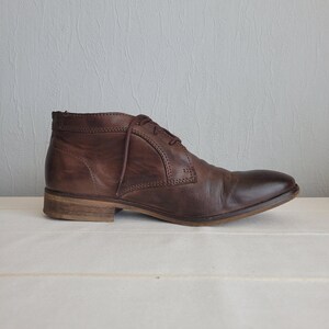 May include: A pair of brown leather ankle boots with laces. The boots have a rounded toe and a low heel.