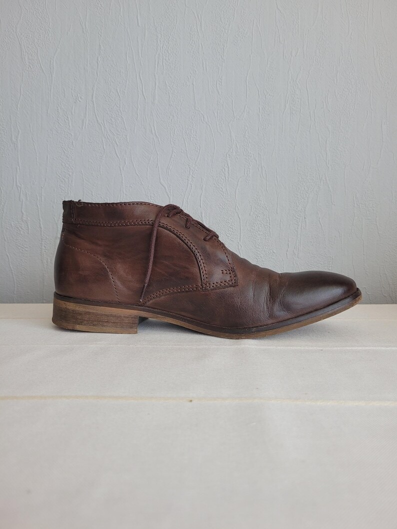 May include: A pair of brown leather ankle boots with laces. The boots have a rounded toe and a low heel.