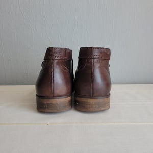 May include: A pair of brown leather ankle boots with a low heel. The boots have a simple design and are made of high-quality leather.