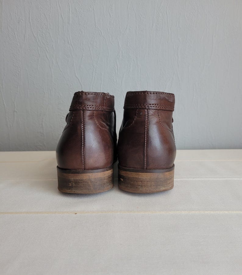 May include: A pair of brown leather ankle boots with a low heel. The boots have a simple design and are made of high-quality leather.