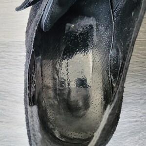 K&ouml;nnte beinhalten: Innenansicht eines schwarzen Wildlederschuhs mit Schnallenverschluss. Der Schuh ist ungef&uuml;ttert und hat eine glatte Ledersohle.