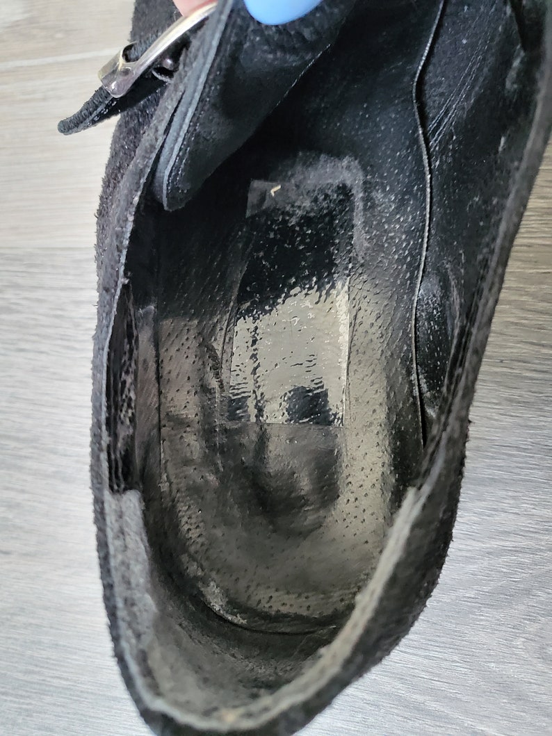 K&ouml;nnte beinhalten: Innenansicht eines schwarzen Wildlederschuhs mit Schnallenverschluss. Der Schuh ist ungef&uuml;ttert und hat eine glatte Ledersohle.