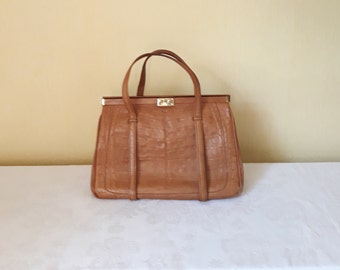 May include: A brown leather handbag with a gold clasp and two top handles.