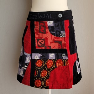 Peut inclure: Une jupe patchwork noire, rouge et grise avec le mot "Desigual" écrit sur la ceinture.