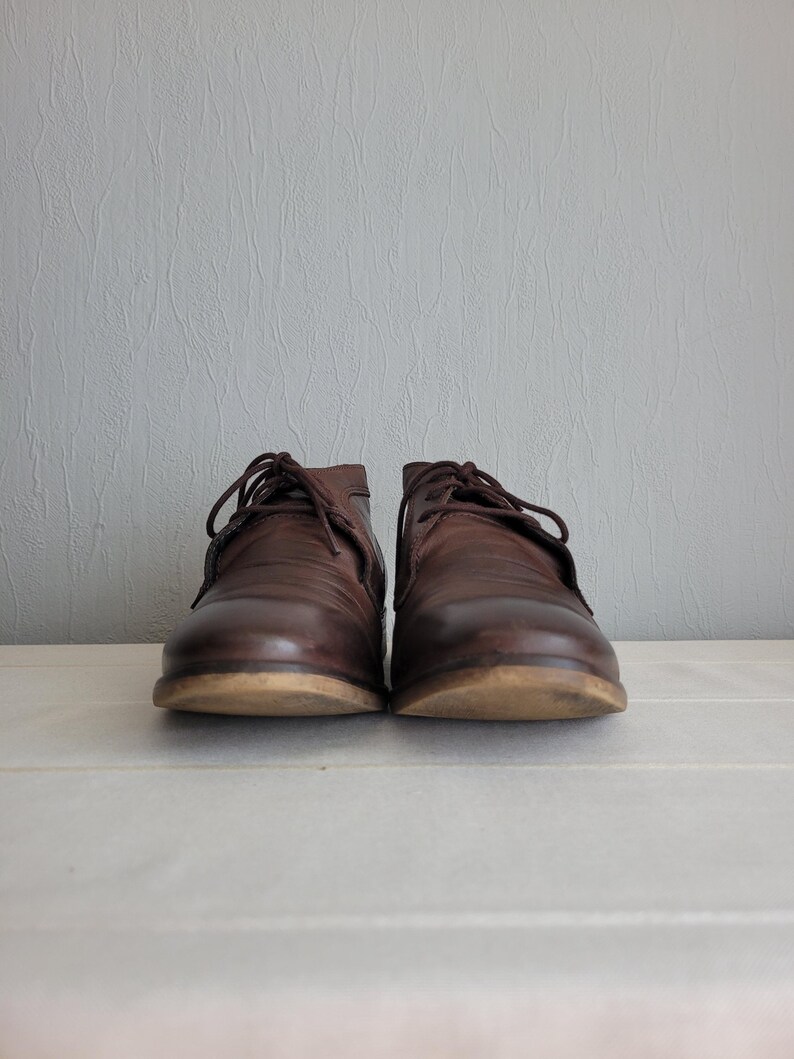 May include: A pair of brown leather lace-up shoes with a slightly rounded toe.