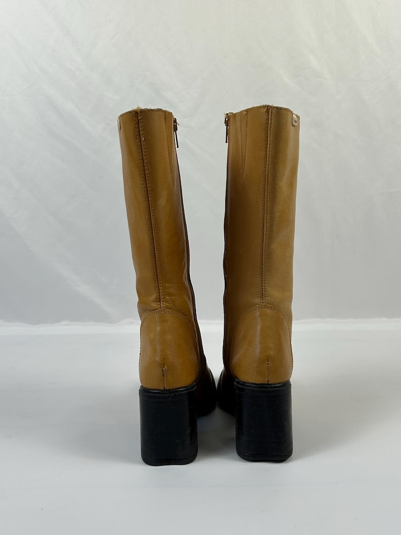 Puede incluir: Botas altas de cuero color marr&oacute;n claro con tacones de bloque negros. Las botas tienen cierre de cremallera y punta redondeada. Est&aacute;n hechas de cuero liso y tienen un ligero brillo. Los tacones miden unos 7,6 cm de alto.