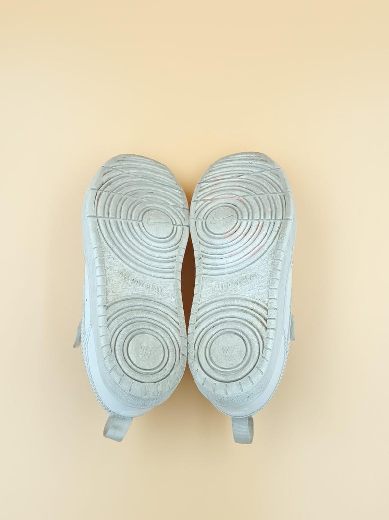 以下が含まれることがあります： テクスチャ加工されたソールが付いた白いスニーカーのペア。ソールは円形の模様で、「Non-Marking」という文字がソールに表示されています。