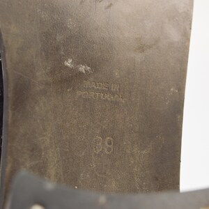 Puede incluir: Primer plano de la suela de un zapato de cuero negro con una plantilla de cuero marr&oacute;n. La plantilla tiene el texto "Made in Portugal" y el n&uacute;mero "39" impreso.