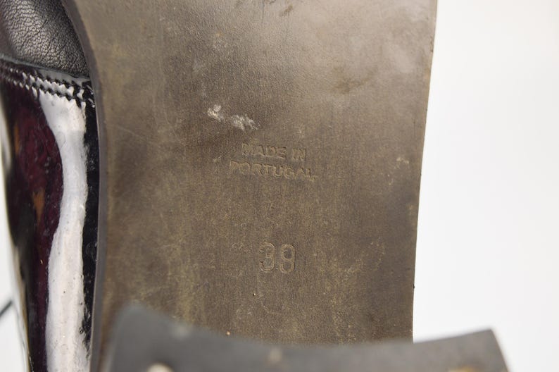 Puede incluir: Primer plano de la suela de un zapato de cuero negro con una plantilla de cuero marr&oacute;n. La plantilla tiene el texto "Made in Portugal" y el n&uacute;mero "39" impreso.