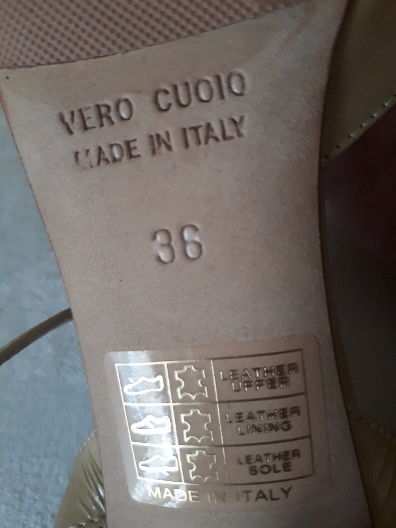May include: Close-up of the bottom of a beige shoe with the text "Vero Cuoio Made in Italy" and the size "38". A label with the text "Leather Upper Leather Lining Leather Sole Made in Italy" is visible.