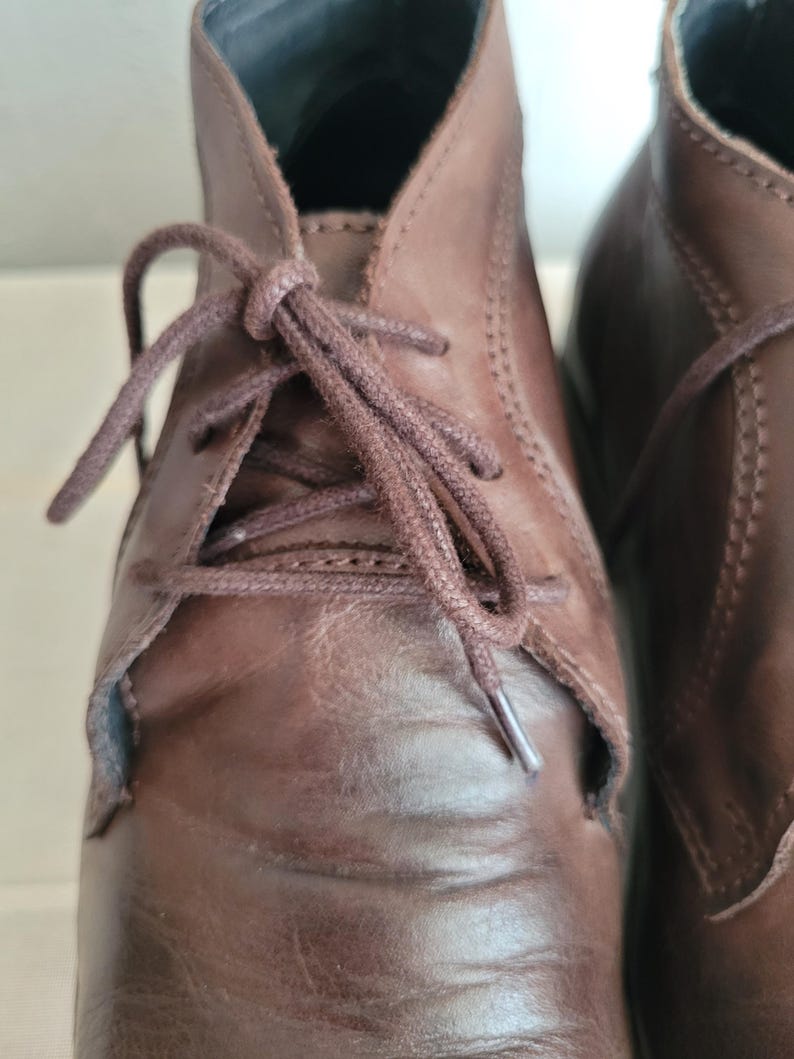 May include: A pair of brown leather ankle boots with laces. The boots have a classic design and are made of high-quality leather.