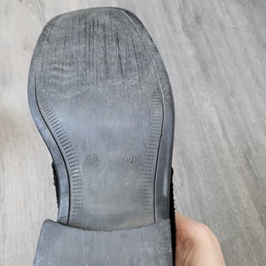 K&ouml;nnte beinhalten: Nahaufnahme der Sohle eines schwarzen Lederstiefels mit einer strukturierten Gummisohle. Die Sohle hat zwei Gr&ouml;&szlig;enmarkierungen: "42" und "26".